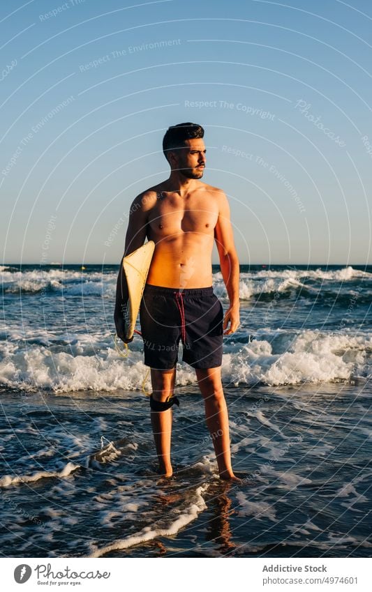 Junger Mann am Strand mit einem Surfbrett Surfer Sonne Schönheit Wasser MEER tragen Freiheit Lebensstile Sonnenaufgang tragend Menschen Sand Sonnenlicht Ferien