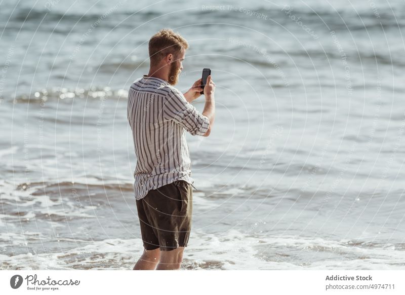Bärtiger Mann, der am Strand Fotos mit seinem Handy macht Telefon Person Natur reisen Bild Mobile Meer Technik & Technologie Landschaft MEER Sommer Zelle Junge