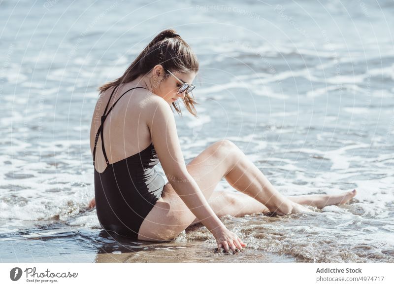 Nachdenkliche junge Frau mit Sonnenbrille am Meeresstrand sitzend Strand MEER Schönheit Sommer sich[Akk] entspannen Behaarung Mädchen Natur schön besinnlich