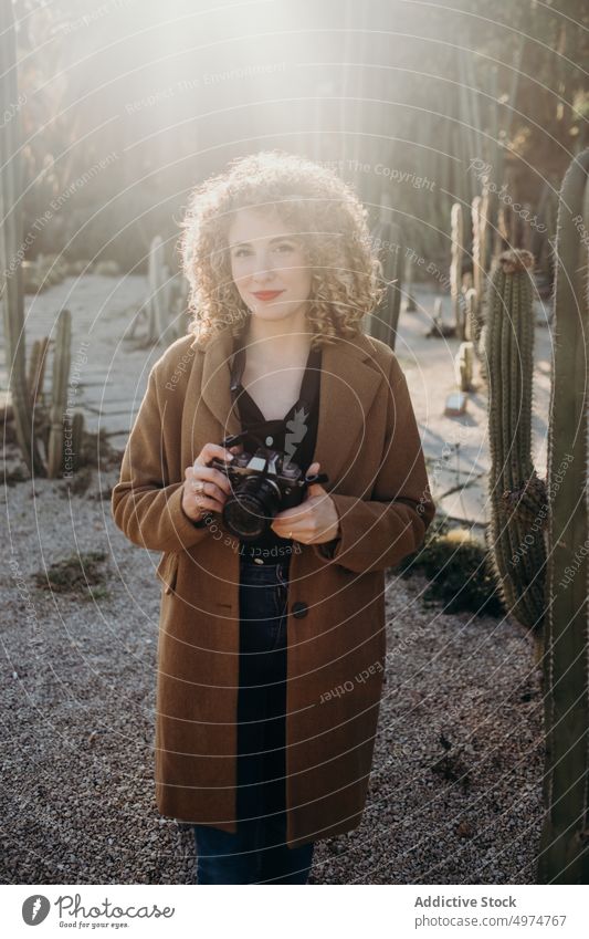Porträt einer schönen, lockigen, blonden Frau mit einer Retro-Kamera Model im Freien Winter Gesicht Accessoire Bekleidung Fotokamera Mantel selbstbewusst