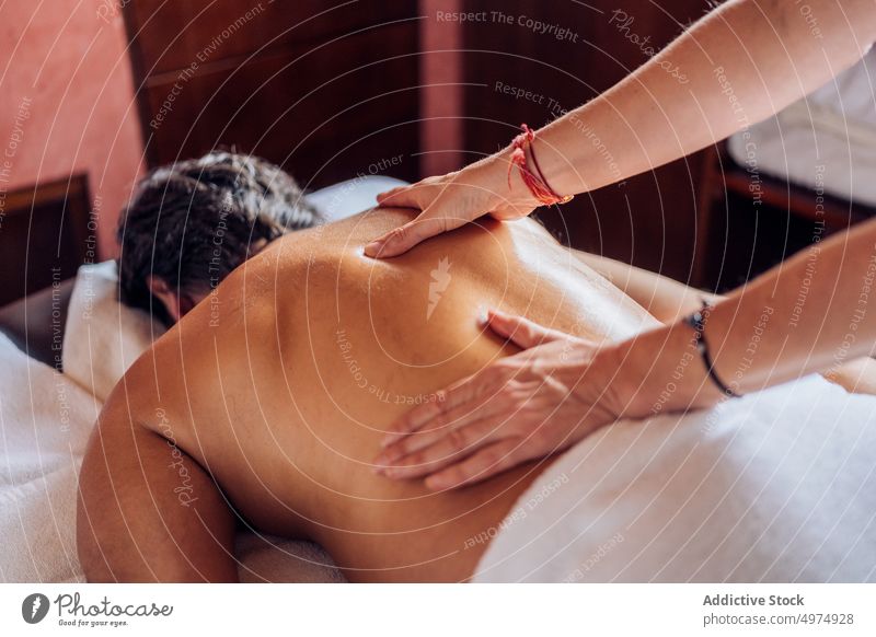 anonyme Masseurin arbeitet mit dem Rücken eines Mannes Therapie Salon Gesundheit Massage Uniform Liege Körper Behandlung Pflege Schönheit Spa ruhen