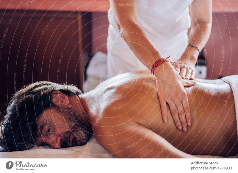 anonyme Masseurin arbeitet mit dem Rücken eines Mannes Therapie Salon Gesundheit Massage Uniform Liege Körper Behandlung Pflege Schönheit Spa ruhen