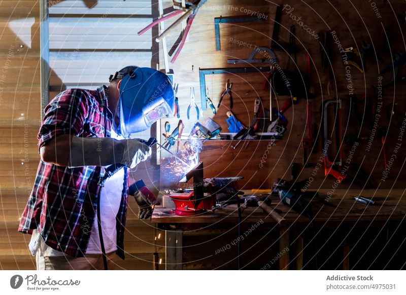 Mann schneidet ein Stück Metall in einer modernen Werkstatt Winkelschleifer Funken Arbeiter Gerät benutzend Schutzhelm Arbeitsplatz Instrument Mechaniker