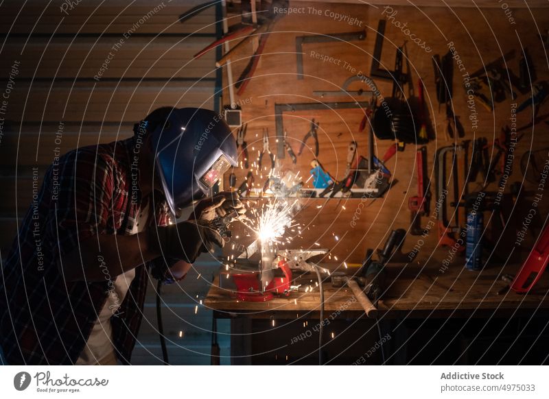 Mann schneidet ein Stück Metall in einer modernen Werkstatt Schutzhelm Winkelschleifer Funken Arbeiter Gerät benutzend Arbeitsplatz Instrument Mechaniker