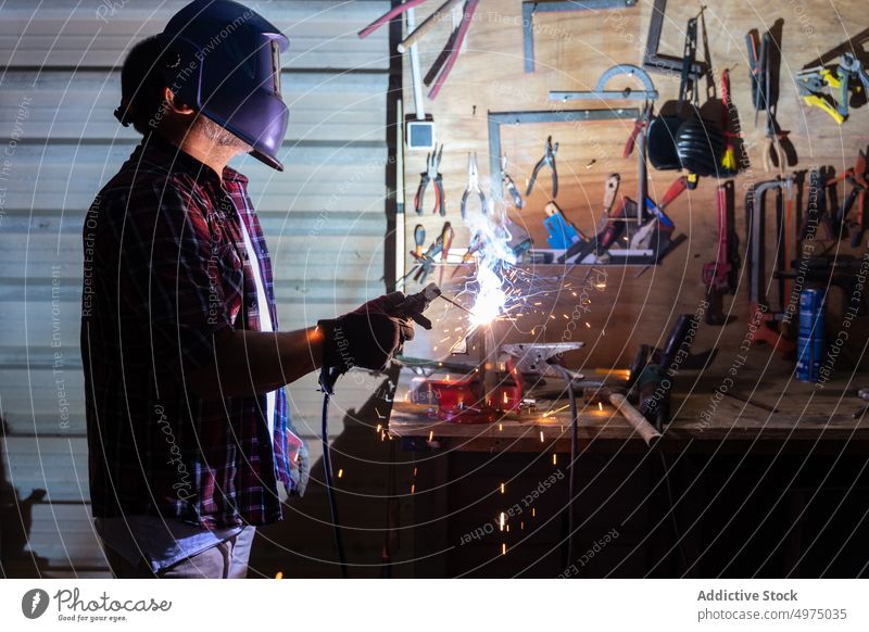 Mann schneidet ein Stück Metall in einer modernen Werkstatt Winkelschleifer Schutzhelm Funken Arbeiter Gerät benutzend Arbeitsplatz Instrument Mechaniker