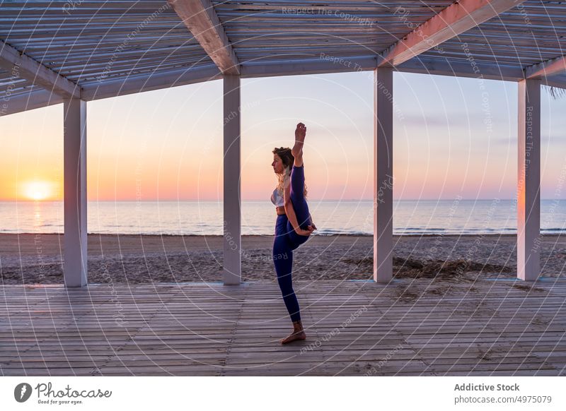 Flexible Frau macht Yoga am Meer bei Sonnenaufgang Pose Seeküste Terrasse ruhig Sportbekleidung üben MEER hölzern anjaneyasana Gelassenheit Gesundheit Harmonie