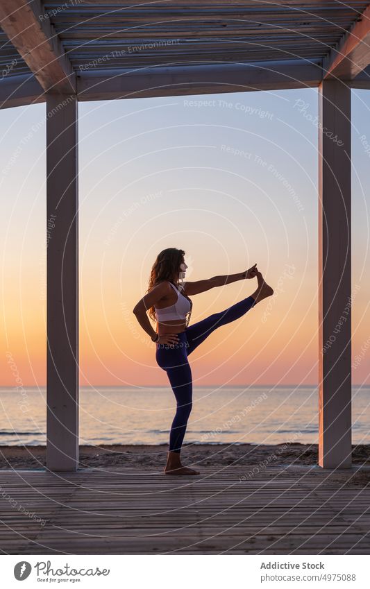 Flexible Frau macht Yoga am Meer bei Sonnenaufgang Pose Seeküste Terrasse ruhig Sportbekleidung üben MEER hölzern anjaneyasana Gelassenheit Gesundheit Harmonie