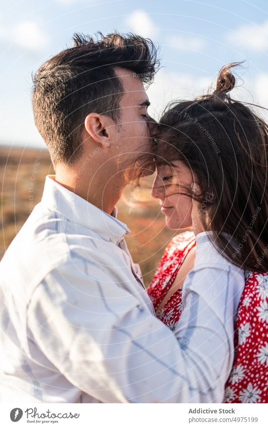Junger Mann küsst die Stirn seiner Freundin mit geschlossenen Augen in der Natur Paar Kuss Gesicht berühren romantisch Augen geschlossen Liebe Feld Zusammensein