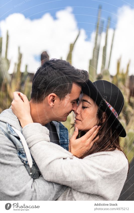 Romantisches junges ethnisches Paar im Kaktusgarten während eines Ausflugs auf Lanzarote Händchenhalten romantisch Garten Pflanze exotisch sich[Akk] entspannen