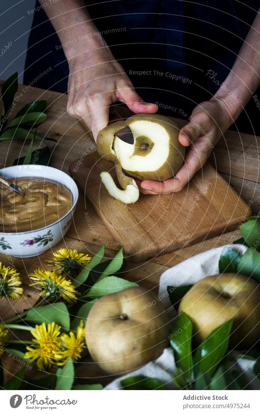 Crop Person schält Apfel über Tisch sich[Akk] schälen Koch Küche heimwärts Messer Dessert frisch Lebensmittel Frucht organisch Vegetarier Veganer rustikal