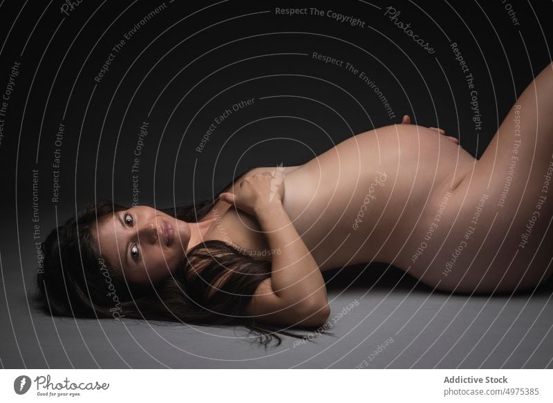 Nackte schwangere Frau auf dem Boden liegend nackt Bauch erwarten mütterlich Mutterschaft Schwangerschaft Glück Liebe Baby Pflege Lächeln Stock Angebot brünett