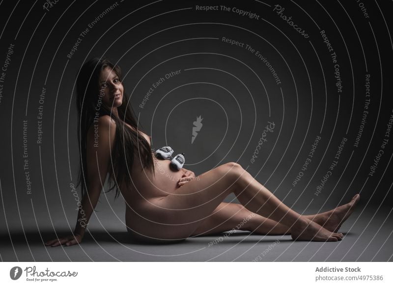 Nackte schwangere Frau mit Schuhen auf dem Bauch nackt erwarten mütterlich Mutterschaft Schwangerschaft Glück Liebe Baby Pflege Lächeln berühren Angebot brünett