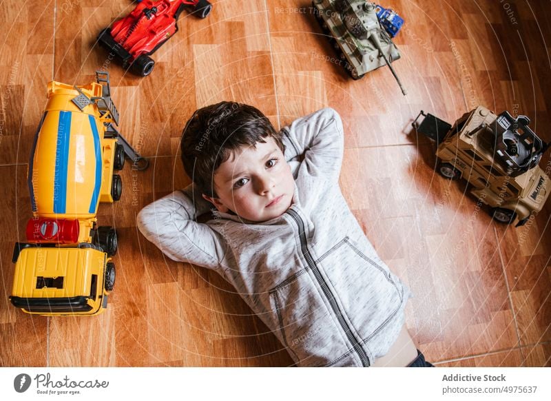 Trauriger Junge spielt mit Spielzeugautos Kind spielen PKW Fahrzeug Stock wenig Lügen männlich Kindheit spielerisch unterhalten heimwärts sorgenfrei Freizeit