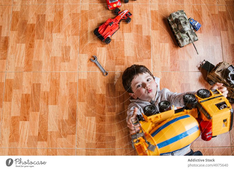 Glücklicher Junge spielt mit Spielzeugautos Kind spielen PKW Fahrzeug heiter Porträt Stock wenig Lügen männlich Kindheit spielerisch unterhalten heimwärts
