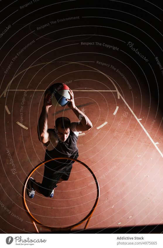 Starker entschlossener Mann, der nachts auf dem Platz Basketball spielt eintauchen Korb Nacht Park Ball springen Schuss Reifen werfen Sportpark Gericht Spiel