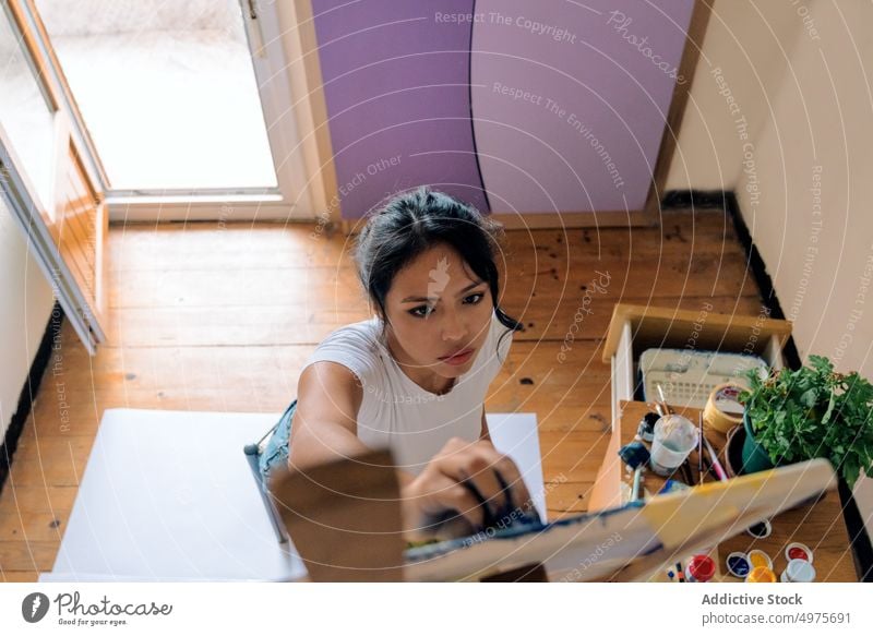 Junge ethnische Frau malt mit Pinsel auf Leinwand zeichnen Farbe Künstler Kunst Hobby Fokus kreieren Bürste Staffelei Talent Kunstwerk Inspiration Fähigkeit