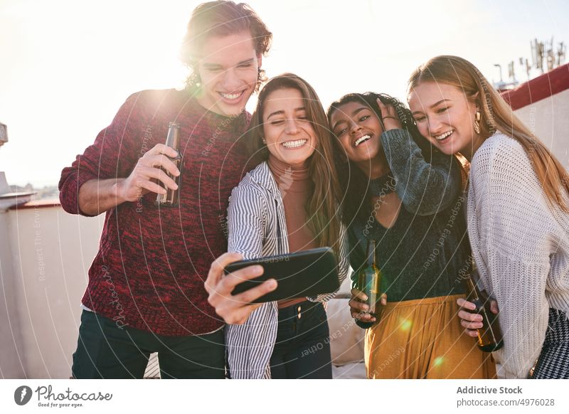 Fröhliche diverse Freunde nehmen Selfie während Party auf Terrasse Smartphone Grimasse Gesicht machen Bier freudig Schnaps Zusammensein Sofa Gerät v-Zeichen