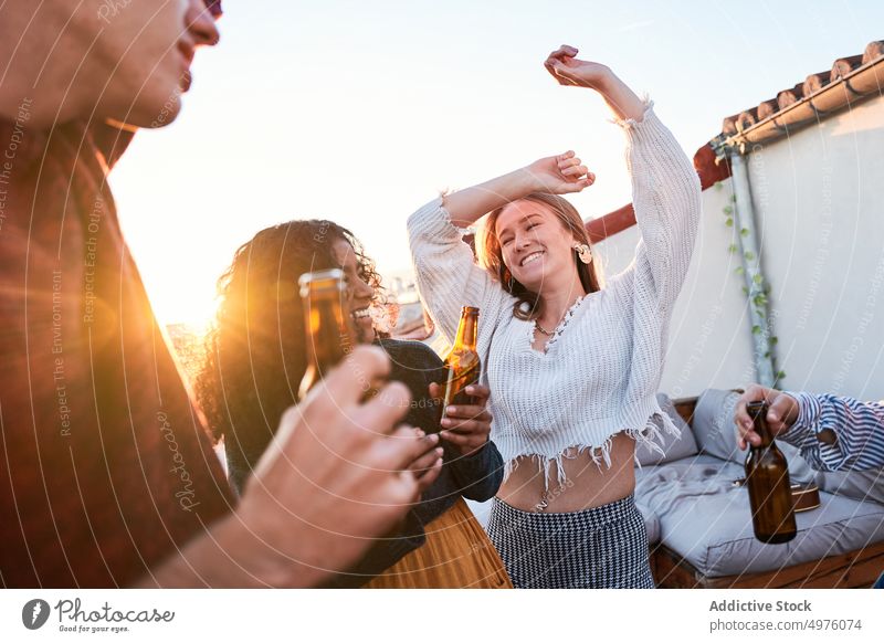 Vergnügte Freunde trinken Bier und tanzen auf dem Dach bei Sonnenuntergang Tanzen Dachterrasse Party Schnaps Glück sorgenfrei Treffpunkt Kälte Getränk