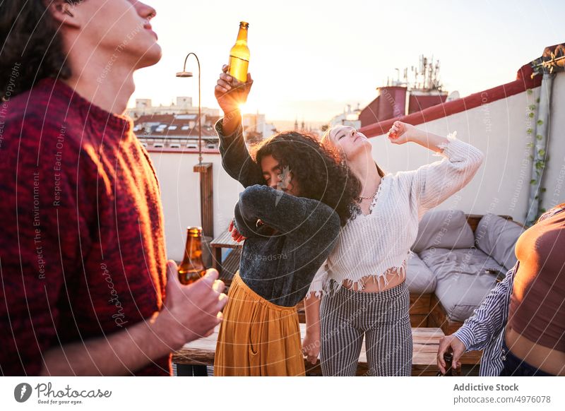 Vergnügte Freunde trinken Bier und tanzen auf dem Dach bei Sonnenuntergang Tanzen Dachterrasse Party Schnaps Glück sorgenfrei Treffpunkt Kälte Getränk