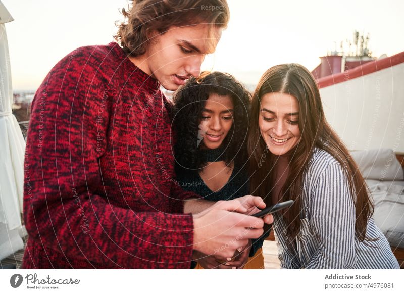 Inhalt diverse Freunde mit Smartphone auf Terrasse benutzend Zusammensein Gerät froh Apparatur zuschauen Freundschaft teilen sich[Akk] sammeln Surfen