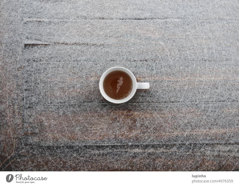 Tasse mit Tee von oben, auf einem Tisch, der leicht mit Schnee bedeckt ist Teetasse angezuckert November Terasse Schwarztee