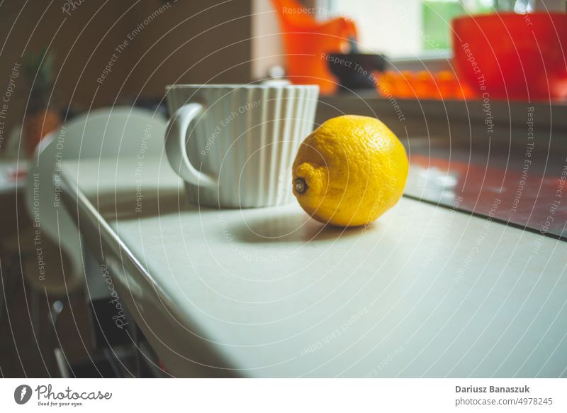 Eine Tasse und eine Zitrone auf der Arbeitsplatte trinken Gesundheit Becher Getränk Frucht Küche Antioxidans Zitrusfrüchte Entzug frisch Kräuterbuch Hintergrund
