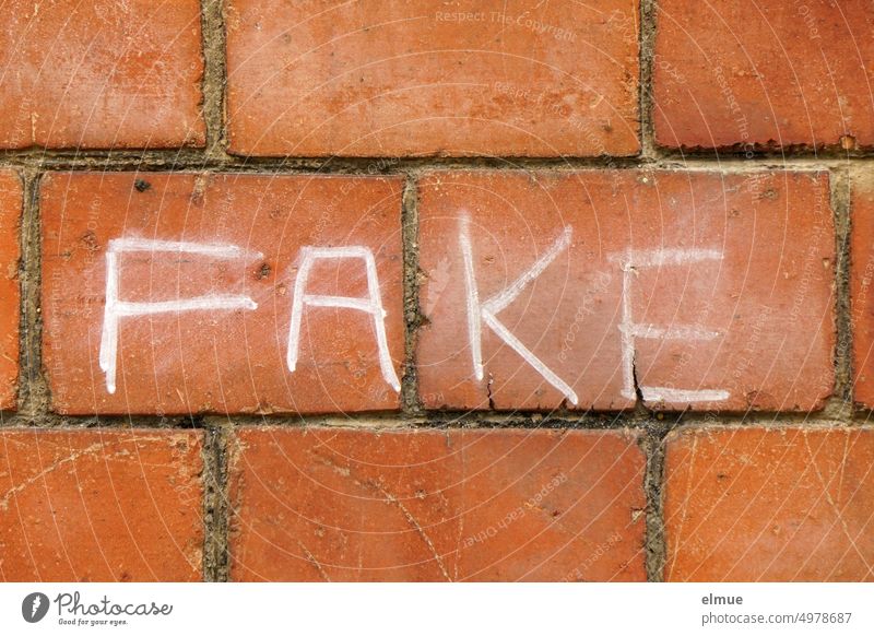 FAKE steht in weißen Großbuchstaben an einer roten Ziegelwand fake Fälschung Anglizismus Schwindel fakenews Jargon Jugendsprache unaufrichtig Schein Schmiererei