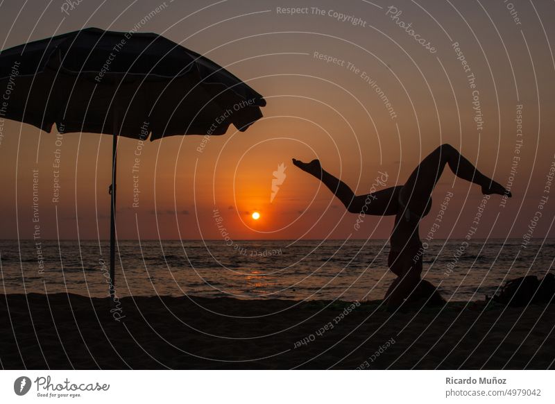 Yoga-Mädchen bei Sonnenuntergang Silhouette Strand-Yoga Yoga bei Sonnenuntergang Sport Sonnenlicht Strandleben Ferien Frauenkörper im Freien Regenschirm feminin