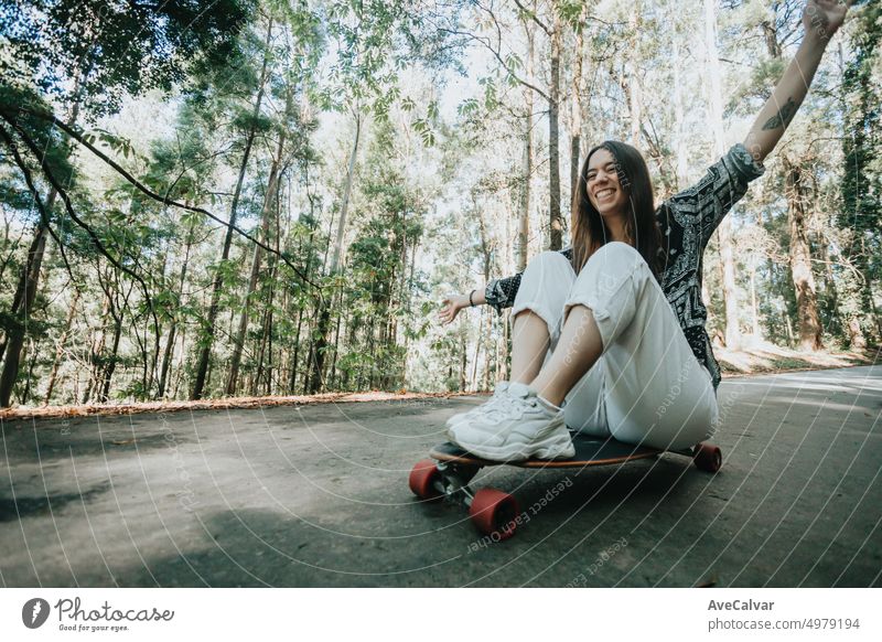 Junge Frau hat Spaß beim Abfahren einer Straße mitten im Wald mit einem Longboard-Skate. Üben im Freien und Extremsportarten, weit weg von der Stadt. Neue Generationen und Freiheit Konzept