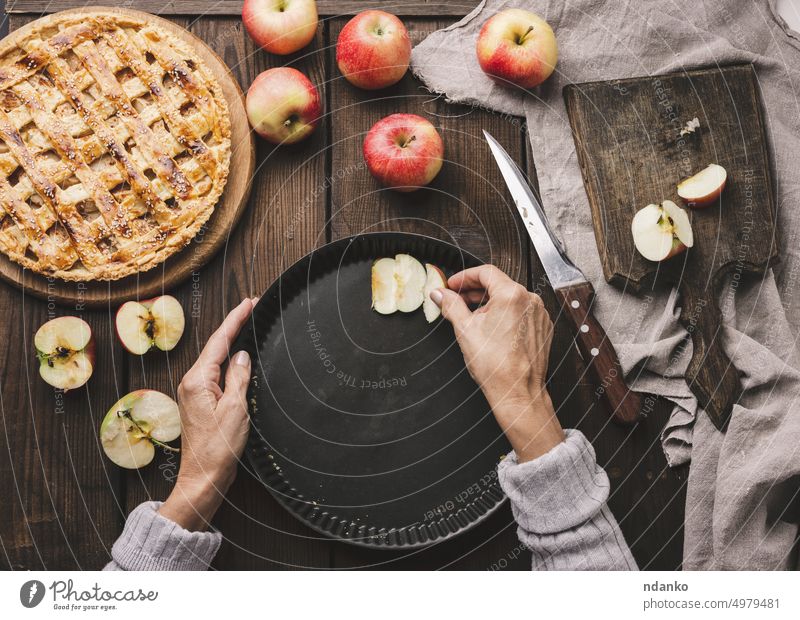 Eine Frau legt Apfelspalten in ein rundes Backblech auf dem Tisch, neben den Zutaten Hand Kruste süß Ernährung Pasteten rustikal Lebensmittel frisch Frucht