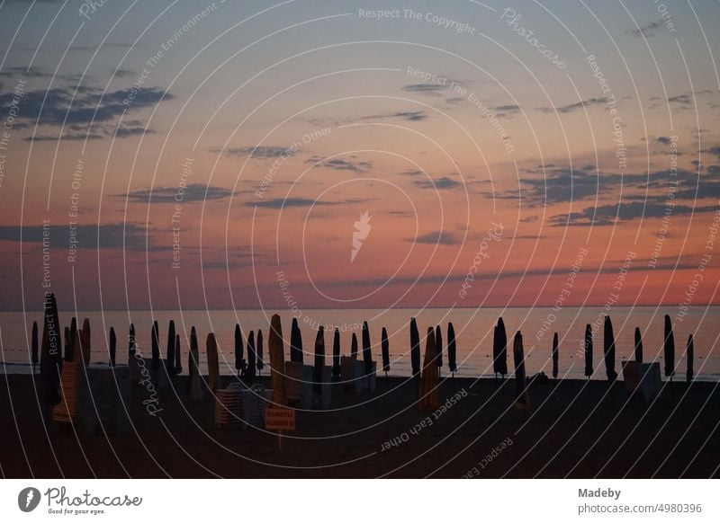 Zusammengeklappte Sonnenschirme nach Sonnenuntergang am Strand von Inkumu am Schwarzen Meer bei Bartin an der Schwarzmeerküste in der Türkei sonnenuntergang