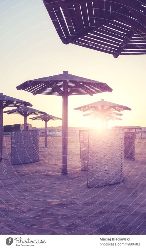 Silhouetten von Sonnenschirmen und Windschutzscheiben am Strand bei Sonnenuntergang, mit Farbtonung. Urlaub friedlich Natur Flucht Sand MEER retro altehrwürdig