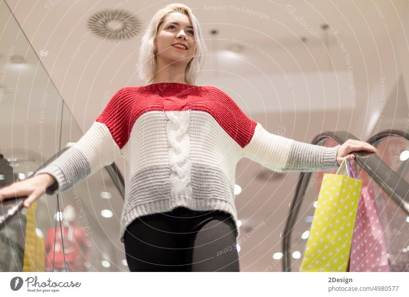 Porträt einer jungen, glücklich lächelnden Frau mit Einkaufstüten auf einer Rolltreppe kaufen Kunde elegant im Innenbereich bewegend positiv Kauf Einzelhandel