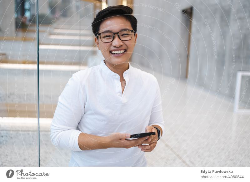 Lächelnder junger Mann mit Mobiltelefon echte Menschen natürlich junger Erwachsener Großstadt urban Schüler positiv heiter Karriere selbstbewusst gelungen