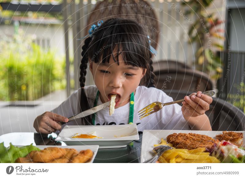 kleines Mädchen asiatischen essen Spiegelei auf Teller am Tisch. wenig Ei gebraten Kind Person Gabel jung Morgen Baby heimwärts Lächeln Küche weiß genießen