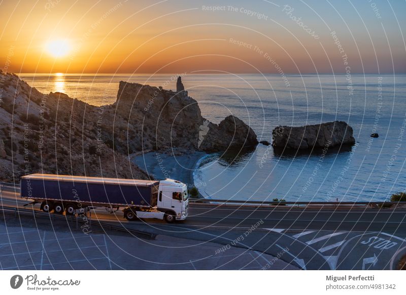 Lastwagen mit Kippmulde fährt in der Morgendämmerung eine Straße am Meer entlang Muldenkipper Anhänger mediterran Fracht fahren Sonnenaufgang Sonnenuntergang
