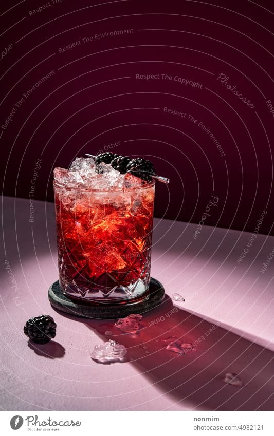 Kalter Sommercocktail mit Eis, garniert mit Brombeeren auf dramatischem Veilchen kalt Cocktail trinken Garnierung violett purpur rot rosa liquide Alkohol