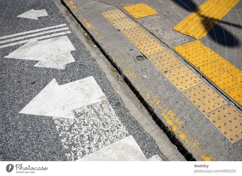Fußgängerüberweg mit Fahrbahnmarkierung in Weiß und taktilem Leitsystem in Gelb auf grauem Asphalt im Sommer bei Sonnenschein im Stadtteil Erenköy in Istanbul am Bosporus in der Türkei