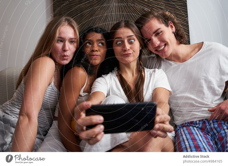 Grimassen schneidende multiethnische Freunde machen ein Selfie zu Hause Gesicht machen Mitbewohner freudig Smartphone heiter Selbstportrait Zusammensein Glück