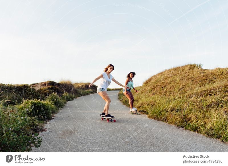 Schöne Frauen Skater Freunde fahren auf der Straße Skateboard Landschaft Spaß schön jung Holzplatte trendy stylisch Skateboarderin Lifestyle Mädchen Sommer