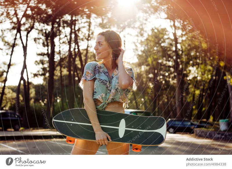 Skater, der im Freien wegschaut und ein Skateboard hält Frau Mode eine Kaukasier Skateboarderin Lifestyle cool Mädchen urban Straße Skateboarding Freizeit