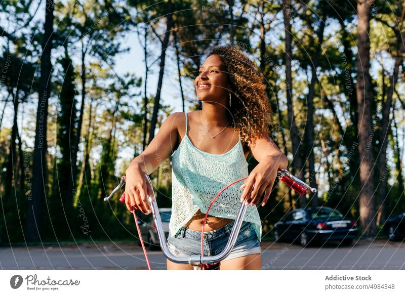 Frau lächelt und schaut weg, während sie auf einem Fahrrad sitzt Sommer Glück Person Lächeln jung hübsch Ethnizität Afrikanisch Lifestyle Porträt ethnisch Park