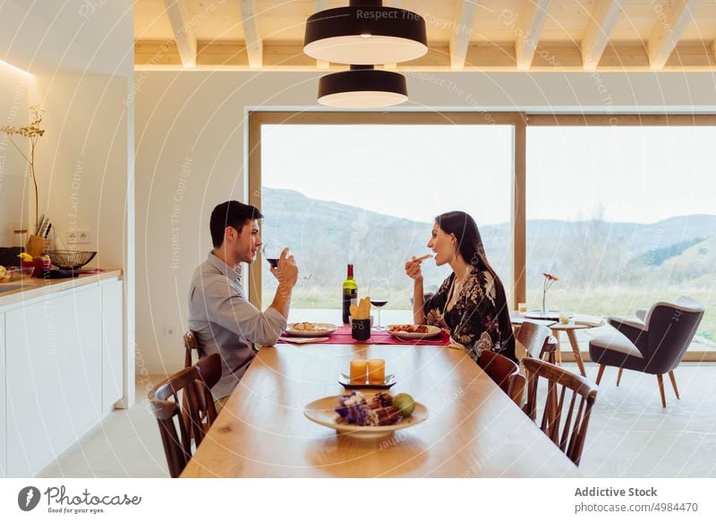 Glückliches Paar beim Essen am Tisch in der Küche Esszimmer hispanisch Teller Glas Wein Lächeln Frau Mann jung attraktiv heiter Getränk Abendessen trinken