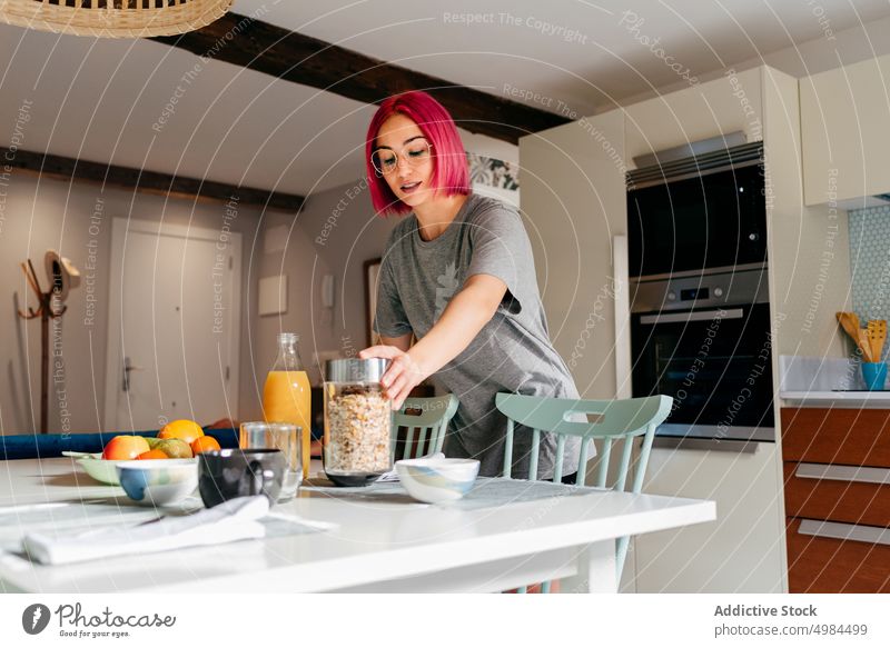 Junge Frau bereitet Frühstück zu Hause vor Morgen heimwärts Müsli vorbereiten Küche Appartement modern heimisch jung Glas gefärbtes Haar rosa informell