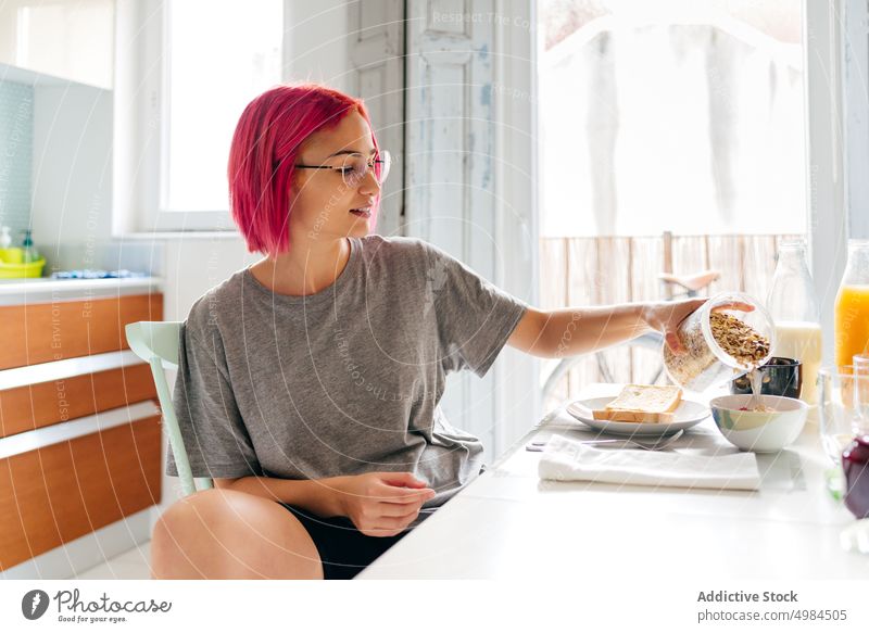 Junge Frau beim gesunden Frühstück zu Hause verschüttete Haferflocken Gesundheit Morgen heimwärts Lächeln Tisch gemütlich essen Küche Appartement modern jung