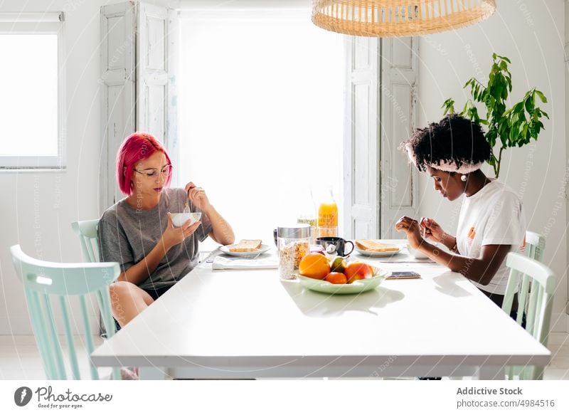 Multiethnische Freunde beim gemeinsamen Frühstück Frauen Morgen heimwärts Müsli essen vielfältig Glück Zusammensein Tisch sitzen Gesundheit Speise Lebensmittel