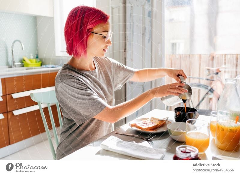Junge Frau schenkt Kaffee zum Frühstück ein eingießen Morgen heimwärts Lächeln Becher Kaffeemaschine jung gefärbtes Haar trinken Getränk heiter ruhen