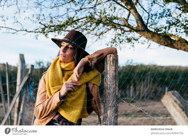 Stilvolle Frau mit Schal und Cowboyhut schön Ranch Natur Stehen Hut Cowgirl trendy nachdenklich träumend brünett Harmonie Zaun jung Landschaft Holz Lehnen