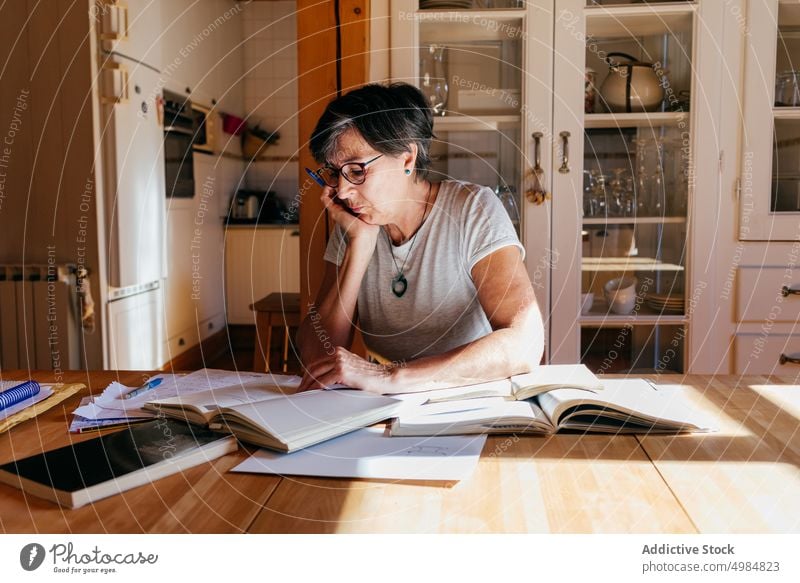 Reife Frau mit Büchern beim Lernen zu Hause Buch lernen lesen beschäftigt Literatur klug professionell Lebensmitte reif Bildung analysieren Papier Fokus