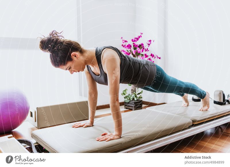 Konzentrierte junge Frau, die Phalakasana Yoga-Pose im Studio ausführt phalakasana Schiffsplanken Wohlbefinden Konzentration Gesundheit Gleichgewicht Ausdauer
